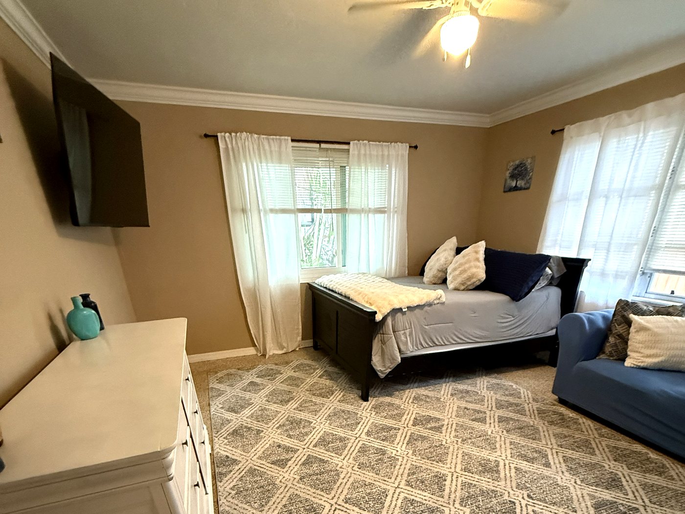 Finished bedroom with painted ceiling, mounted TV, curtains and cleaned carpet