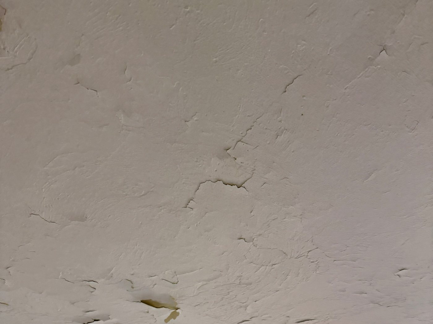 Bedroom ceiling with paint blistering and flaking away in patches