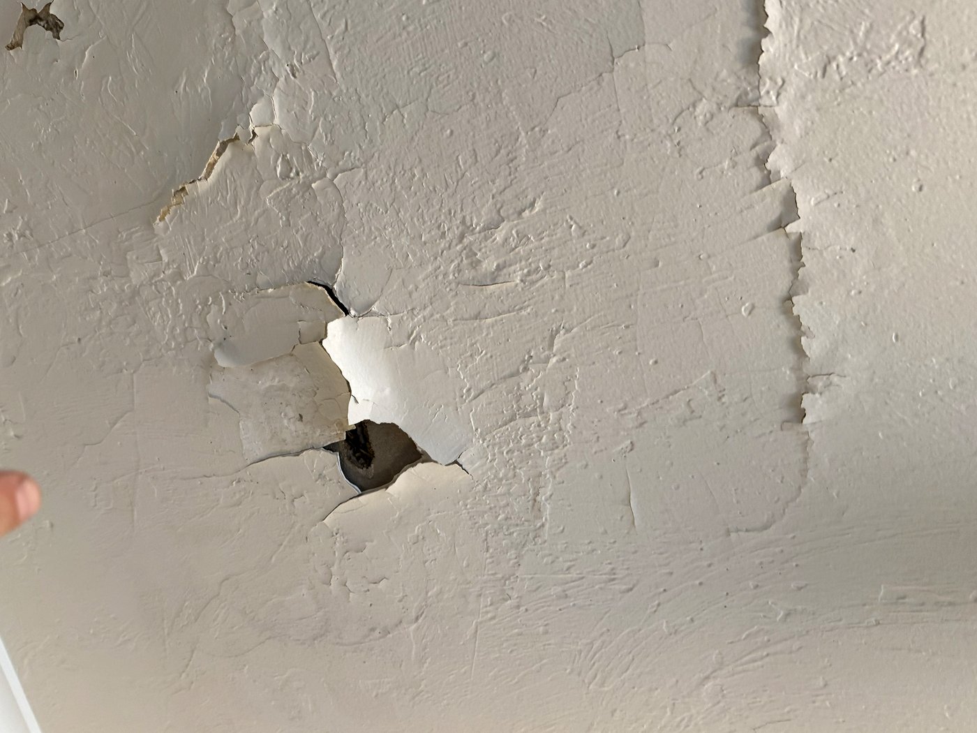 Ceiling with paint lifted away and a hole opened through to the substrate