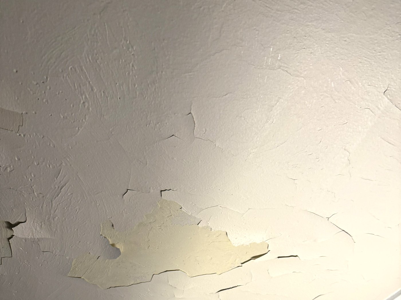 Another angle of the same ceiling showing lifted paint and exposed substrate