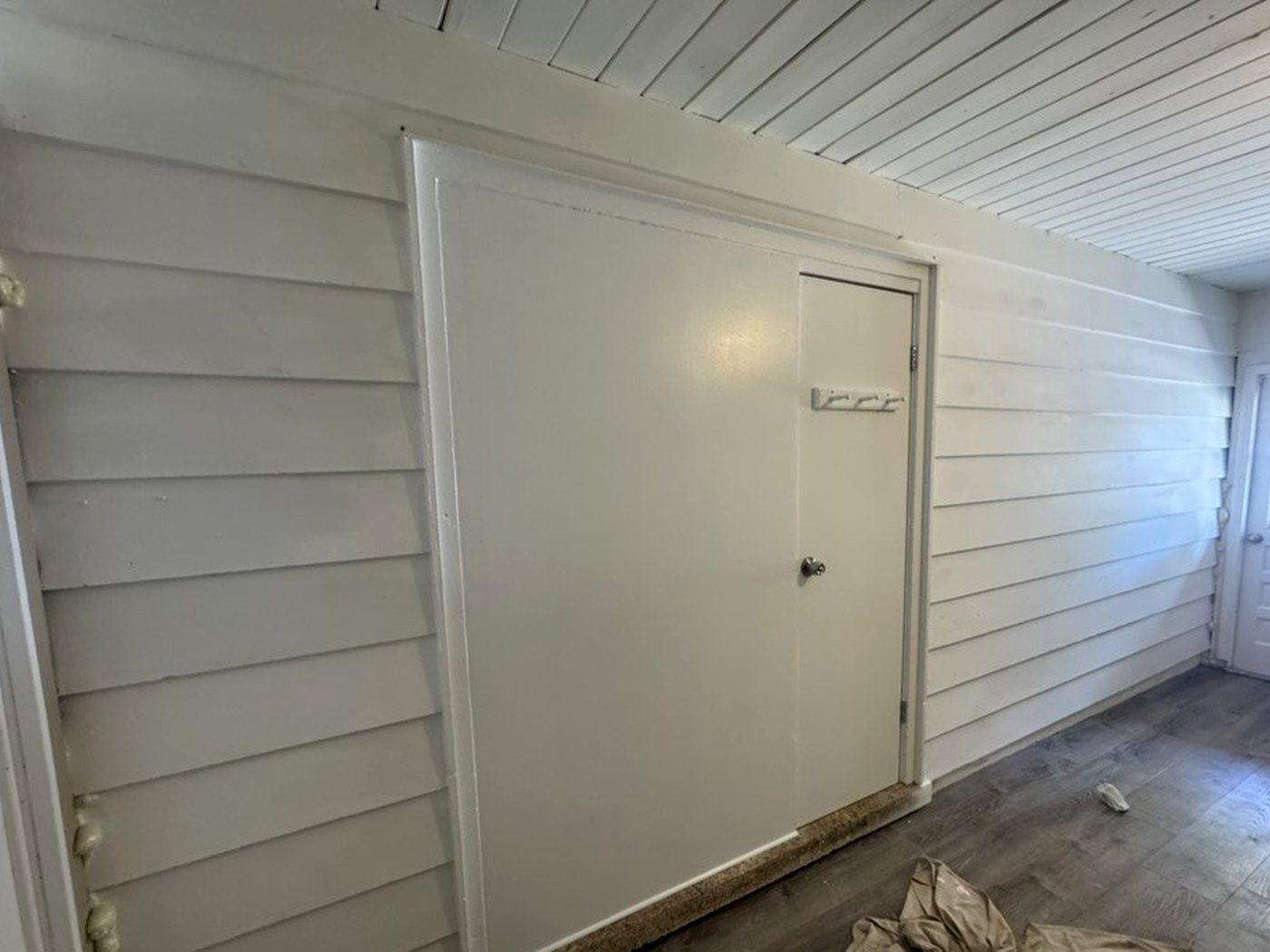 The completed wall and door, finished with siding-style boards and painted white